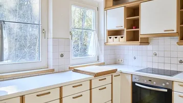 Helle Küche mit weißen Fliesen, Holzschränken und einem modernen Induktionskochfeld.