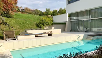 Außenbereich mit großem Swimmingpool und Liegeflächen, umgeben von einer grünen Hügellandschaft.