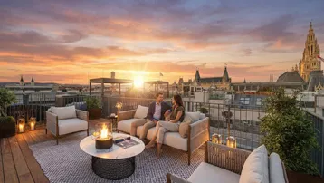 Sonnenuntergang auf einer luxuriösen Dachterrasse mit Stadtblick und gemütlicher Sitzgruppe.