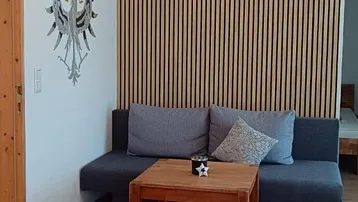 Gemütliches Wohnzimmer mit modernem Sofa, Holztisch und dekorativer Lamellenwand.