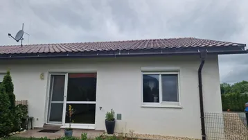 Außenansicht eines modernen Einfamilienhauses mit Satteldach, weißer Fassade und Zugang zum Garten.
