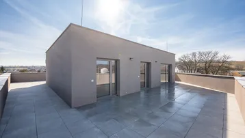 Große, sonnige Dachterrasse mit modernen Fliesen und Blick auf die Umgebung.