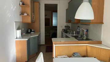 Funktionale Küche mit Holz- und mintgrünen Schränken, Spüle und einem kleinen Essbereich.
