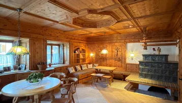 Gemütlicher Wohn- und Essbereich im alpinen Stil mit Holztäfelung und traditionellem Kachelofen.