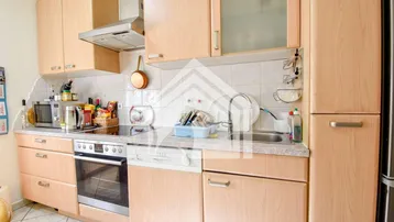 Einbauküche mit hellen Holzschränken, integrierten Geräten und Fliesenrückwand.