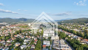 Weitläufige Luftaufnahme einer Stadt mit Bergen im Hintergrund und vielen Wohnhäusern.