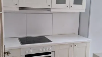 Funktionale Einbauküche mit weißen Schränken, Herd und Backofen, bereit zur sofortigen Nutzung.