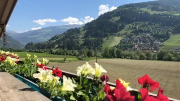 Balkon mit bunten Blumenkästen und Panoramablick auf die umliegende Bergwelt.