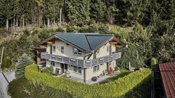 Traditionelles Haus in den Bergen mit Balkonen und umgeben von üppiger Natur und Wald.