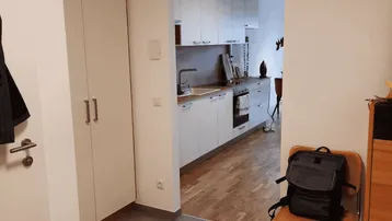 Heller Eingangsbereich mit Einbauschrank und Blick in die moderne Küche mit Holzfußboden.