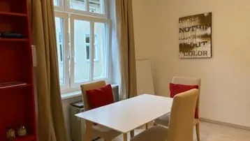Heller Wohn- und Essbereich mit modernem Tisch, Stühlen und Blick auf die Straße durch das Fenster.
