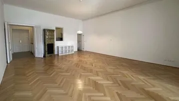 Geräumiges Wohnzimmer in einer gepflegten Altbauwohnung mit Fischgrätparkett und traditionellem Kachelofen.