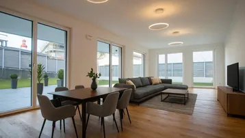 Heller Wohn-Essbereich mit Holzboden, modernen Leuchten und Zugang zur Terrasse.