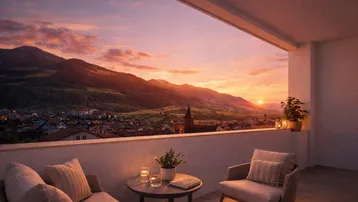 Geräumiger Balkon mit gemütlichen Sitzgelegenheiten und atemberaubendem Blick auf die Berge bei Sonnenuntergang.
