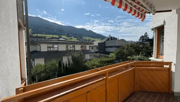 Geräumiger Balkon mit Holzelementen, Markise und weitem Blick auf die umliegende Berglandschaft.