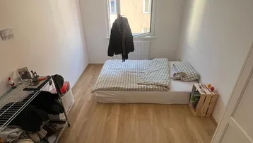 Helles Schlafzimmer mit Holzboden, einem Einzelbett und einem Fenster mit Blick nach draußen.