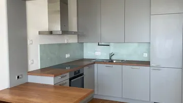 Moderne Einbauküche mit grauen Fronten, Holzarbeitsplatte und integriertem Essbereich.