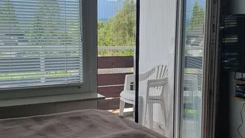 Schlafzimmer mit Zugang zum Balkon und weitem Blick auf die umliegende Berglandschaft.