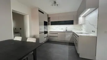 Moderne Küche mit hellen Schränken, Marmoroptik-Arbeitsplatten und dunklem Fliesenboden.