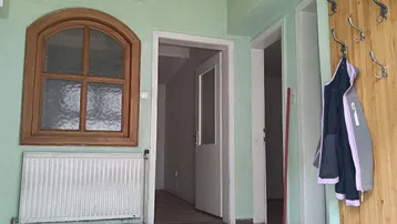 Eingangsbereich mit Fliesenboden, Holzfenster und Deckenventilator, der auf Renovierung wartet.