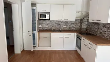 Moderne Einbauküche mit weißen Schränken, Holz-Arbeitsplatte und integrierten Geräten.