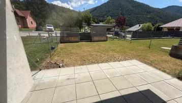 Gepflasterte Terrasse mit Blick auf einen Garten und die umliegende Berglandschaft.