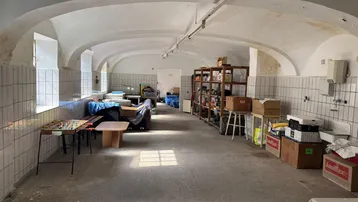 Geräumiger Kellerraum mit Gewölbedecken, gefliesten Wänden und Betonboden, genutzt als Lager und Freizeitbereich.
