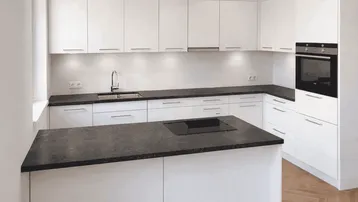 Moderne Einbauküche mit weißen Schränken, dunkler Arbeitsplatte und Kochinsel.