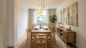 Heller Essbereich mit Holztisch, modernen Stühlen und einem Sideboard unter dem Fenster.