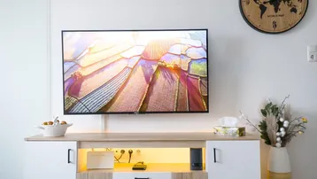 Helles Wohnzimmer mit modernem TV-Möbel, Holzboden und Wanduhr.