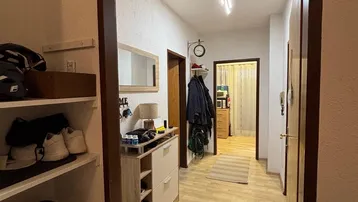 Heller Eingangsbereich mit praktischen Schuhregalen und Garderobe, der zu weiteren Räumen führt.