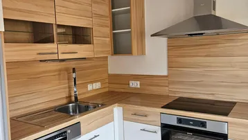 Moderne Einbauküche mit Holzoptik-Fronten, weißen Unterschränken und integrierten Geräten.