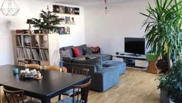 Geräumiger offener Wohn- und Essbereich mit Parkettboden, großem Sofa und Esstisch.