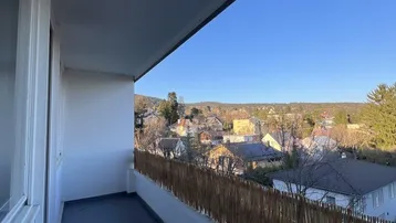 Sonniger Balkon mit Fliesenboden und weitem Blick über die umliegende Wohngegend.