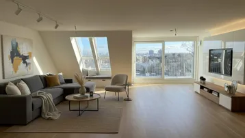 Helles, modern eingerichtetes Wohnzimmer mit großem Sofa, Holzboden und weitem Stadtblick.