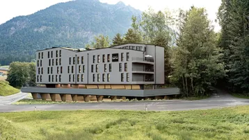 Modernes Gebäude in alpiner Landschaft mit großen Fenstern und Balkonen, umgeben von Natur.