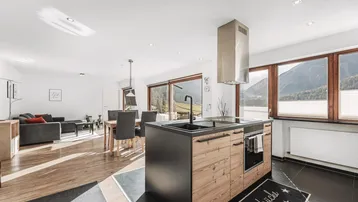 Offene Küche mit moderner Insel, integrierten Geräten und direktem Blick auf die Berge.