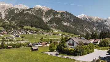 Panoramablick auf ein charmantes Haus in einer malerischen Berglandschaft mit grünen Wiesen.
