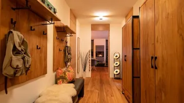 Heller Flur mit Holzboden, Garderobe und Blick auf den Kamin im Wohnbereich.