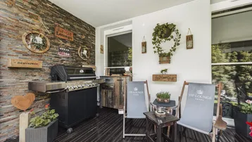 Überdachte Terrasse mit Grillbereich und gemütlichen Sitzgelegenheiten, ideal für gesellige Abende.