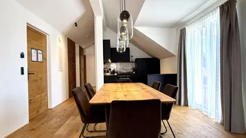 Moderner Essbereich mit Holztisch und Stühlen, angrenzend an eine stilvolle schwarze Küche unter Dachschrägen.
