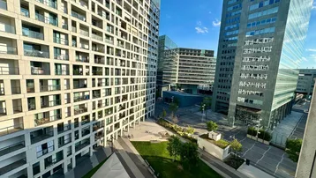 Moderne Wohngebäude mit Balkonen und einer begrünten Außenanlage unter blauem Himmel.