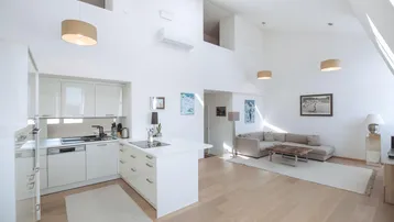Helles, offenes Wohnzimmer mit integrierter Küche, hohen Decken und Dachfenstern für viel Licht.