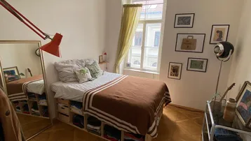Helles Schlafzimmer mit gemütlichem Bett, großem Spiegel und elegantem Parkettboden.