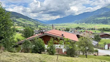 Haus mit rotem Dach in einer malerischen Berglandschaft mit weitem Blick ins Tal.