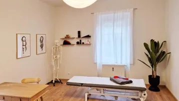 Heller Behandlungsraum mit Holzboden, Therapieliege und einem Skelettmodell, ideal für Physiotherapie oder Praxis.