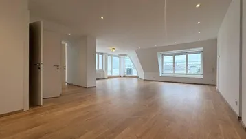 Geräumiges und helles Wohnzimmer mit Holzboden, Dachschrägen und großen Fenstern.