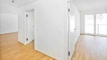 Heller Flur mit Holzboden und Zugang zu verschiedenen Räumen sowie einem Balkon.