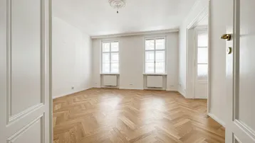 Helles Zimmer mit Fischgrätparkett, hohen Decken und Stuckelementen, ideal als Wohn- oder Schlafzimmer.