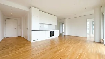 Heller offener Wohnbereich mit integrierter moderner Küche und elegantem Holzparkettboden.
